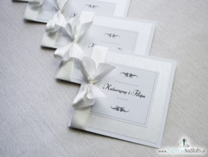 Bardzo prestiżowe zaproszenia ślubne z kokardką w kolorze ecru, dwoma cyrkoniami, kilkoma warstwami ciekawego papieru (np. z motywem srebrnych słojów drzew) oraz wklejanym wnętrzem. ZAP-71-30
