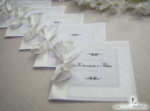 Bardzo prestiżowe zaproszenia ślubne z kokardką w kolorze ecru, dwoma cyrkoniami, kilkoma warstwami ciekawego papieru (np. z motywem srebrnych słojów drzew) oraz wklejanym wnętrzem. ZAP-71-30