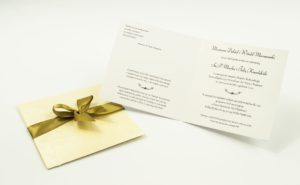 Dwuczęściowe zaproszenia z charakterystyczną kopertą w kolorze kremowym z wytłoczonymi kwiatami, jasnobrązową satynową wstążką oraz wkładką. ZAP-45-66